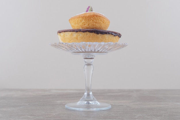 Photo gratuite gâteau au chocolat et gâteau garni de poudre de vanille empilés sur un socle en verre sur marbre