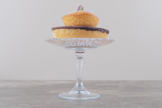 Gâteau au chocolat et gâteau garni de poudre de vanille empilés sur un socle en verre sur marbre