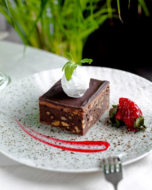 Gâteau au chocolat avec noix, crème glacée sur le dessus et fraises 1