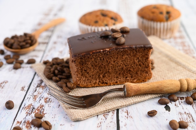 Gâteau au chocolat sur le sac et les grains de café avec une fourchette sur une table en bois.