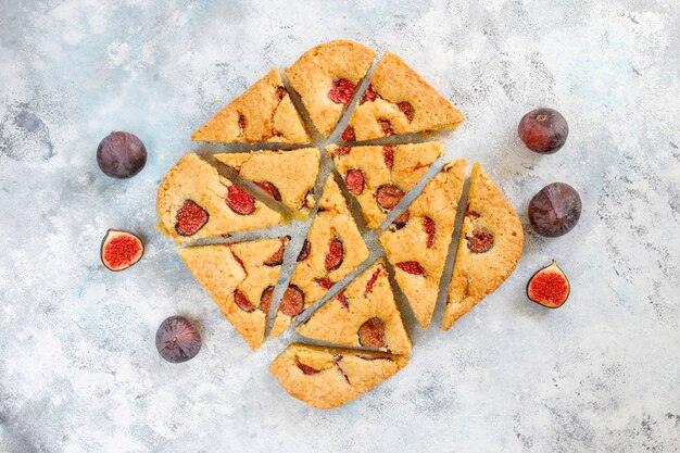 Gâteau aux figues avec des figues fraîches sur fond de béton gris.