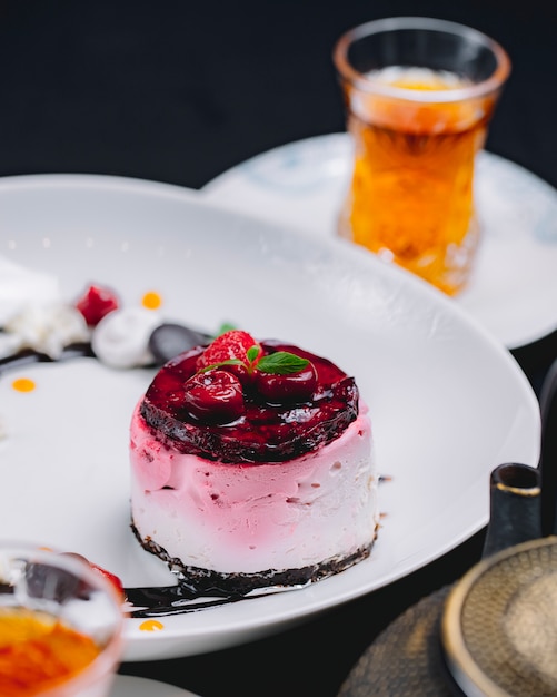 Gâteau aux petits fruits avec lait soufflé cerise fraise sauce au chocolat thé vue latérale