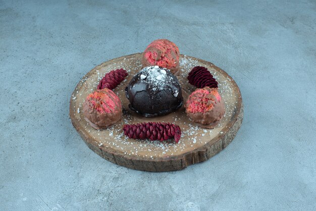 Photo gratuite gâteau, biscuits et pommes de pin sur une planche en marbre.