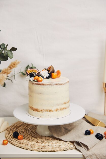 Gâteau blanc aux baies et fruits de la passion à côté d'une plante derrière un fond blanc