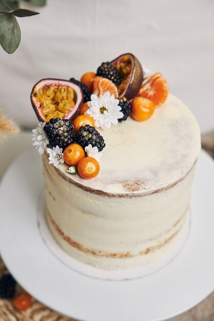 Gâteau blanc aux baies et fruits de la passion à côté d'une plante derrière un fond blanc