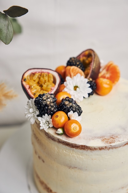 Gâteau blanc aux baies et fruits de la passion à côté d'une plante