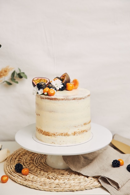 Gâteau blanc aux baies et fruits de la passion avec des plantes derrière