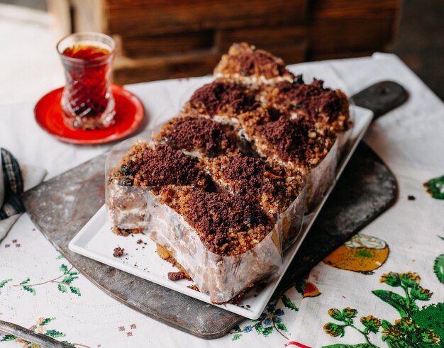 gâteau brun tranché délicieux délicieux en poudre à l'intérieur de la plaque blanche avec du thé chaud