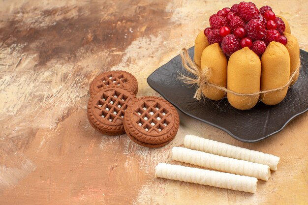 Un gâteau cadeau et des biscuits sur des assiettes brunes fruits sur la vue de dessus de table de couleur mixte