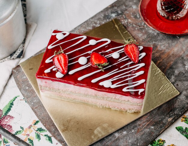 Gâteau carré crème fraise rouge en tranches avec du thé chaud sur un bureau gris