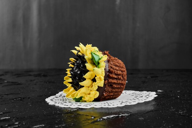 Un gâteau en forme de tournesol sur une surface noire.