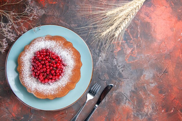 un gâteau un gâteau aux groseilles rouges sur l'assiette branches couteau et fourchette