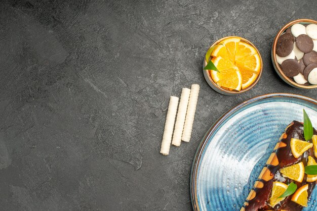 Gâteau moelleux décoré d'orange et de chocolat et de gâteaux sur table noire