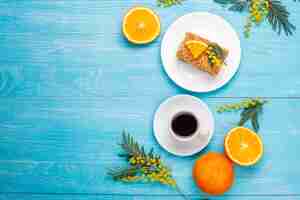 Photo gratuite gâteau à l'orange décoré de tranches d'orange fraîches et de fleurs de mimosa à la lumière