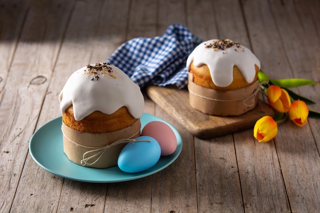 Gâteau de Pâques traditionnel, oeufs colorés et tulipes sur table en bois.