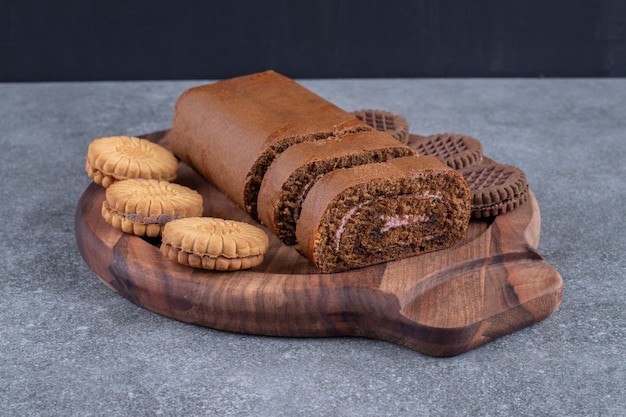 Gâteau roulé au chocolat et biscuits sur plaque de bois