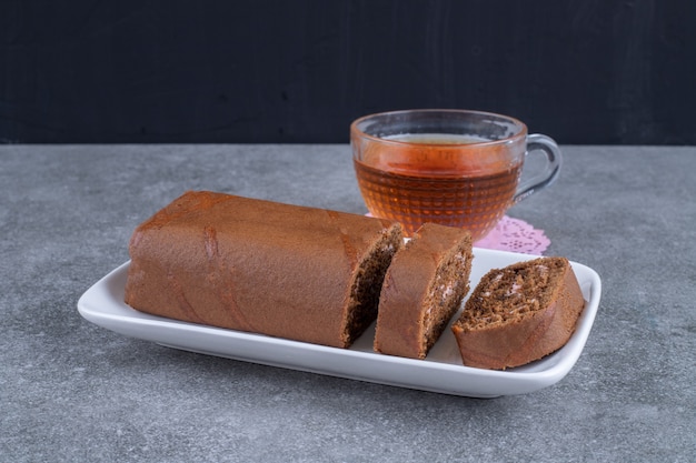 Gâteau roulé au chocolat et tasse de thé sur une surface en marbre