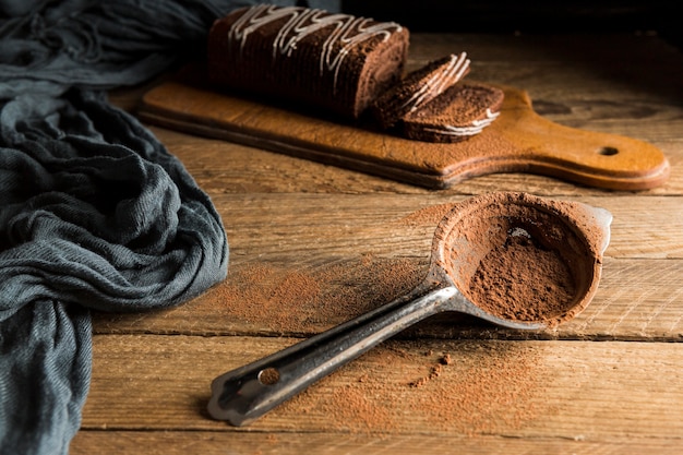 Gâteau roulé au chocolat tranché à angle élevé et passoire avec poudre de cacao