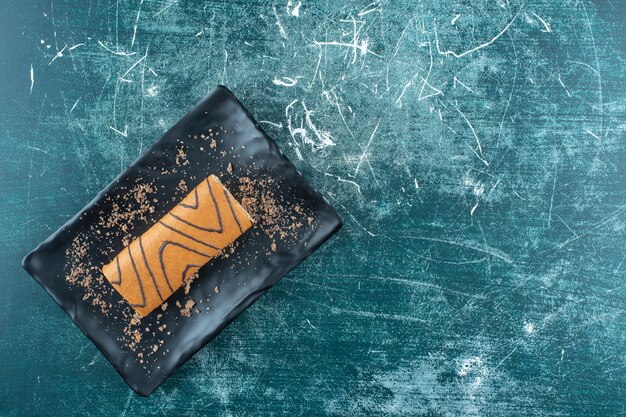 Gâteau roulé savoureux sur une plaque noire , sur fond bleu. photo de haute qualité