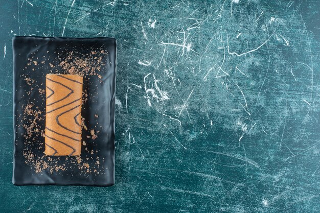 Gâteau roulé savoureux sur une plaque noire , sur fond bleu. photo de haute qualité