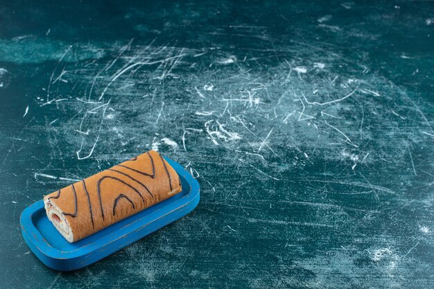 Gâteau roulé savoureux sur une plaque noire , sur fond bleu. photo de haute qualité