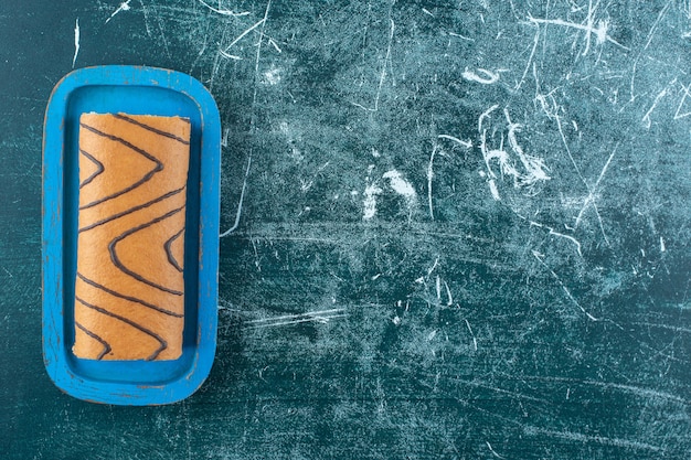 Gâteau roulé savoureux sur une plaque noire , sur fond bleu. photo de haute qualité