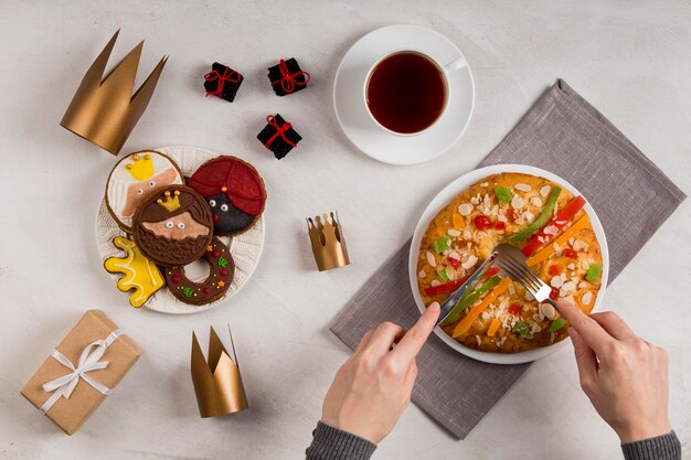 Photo gratuite gâteau savoureux épiphanie heureuse et personne coupant le dessert