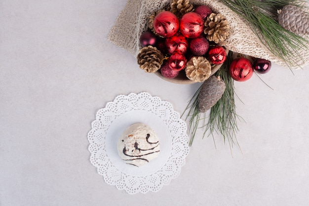 Gâteau sucré sur assiette et jouets de Noël sur une surface blanche