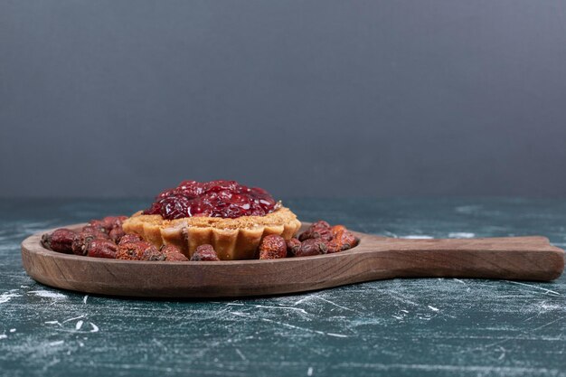 Gâteau tarte sur planche de bois avec des cynorrhodons séchés.