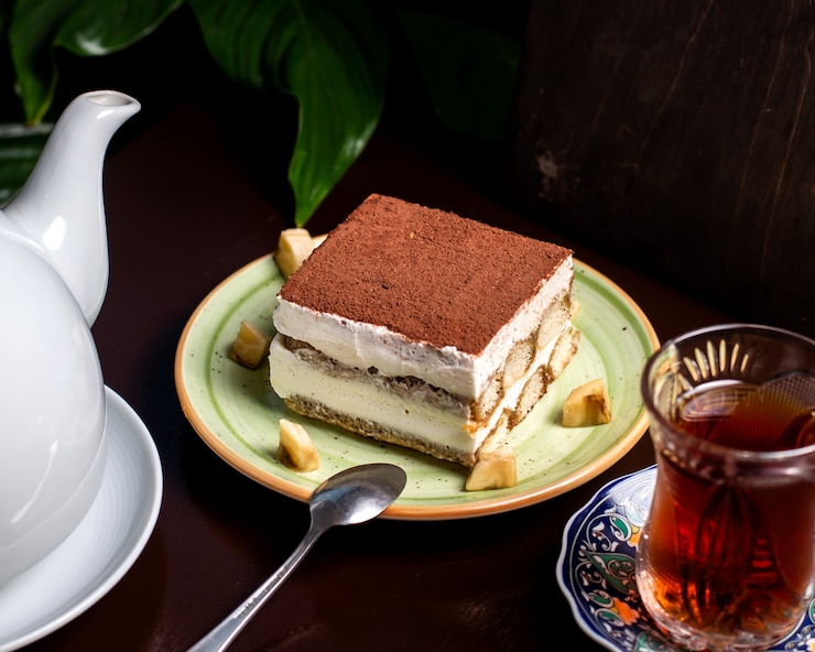 Photo gratuit gâteau de tiramisu avec de la poudre de cacao sur le dessus servi avec du thé