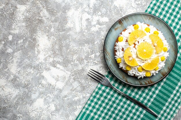 Gâteau vue de dessus avec crème pâtissière et citron sur une fourchette à assiette ronde sur une nappe à carreaux blanc vert