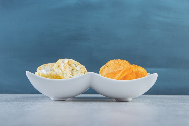 Gâteaux de riz complet croustillants et chips épicées dans des bols blancs.