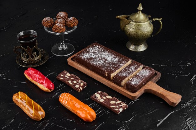 Gaufre au chocolat sur un plateau en bois avec des biscuits et des éclairs.