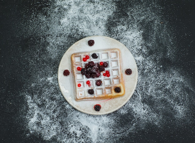 Gaufre dans une assiette avec des mûres vue de dessus sur dark