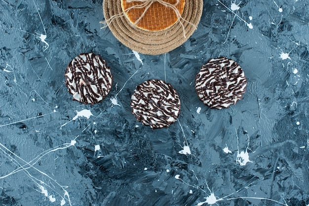 Gaufre sur un dessous de plat à côté d'un biscuit au chocolat, sur la table bleue.