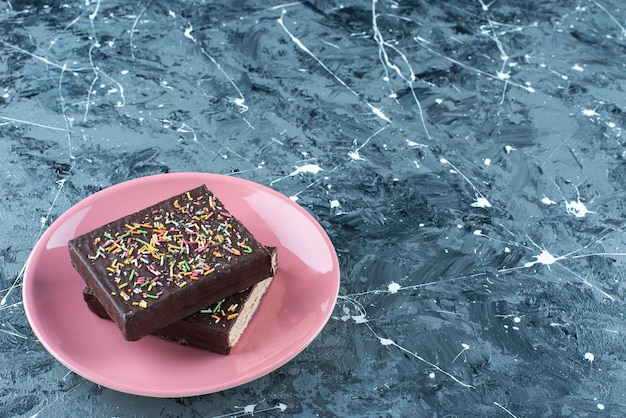 Gaufre enrobée de chocolat en tranches sur une assiette, sur la table bleue.