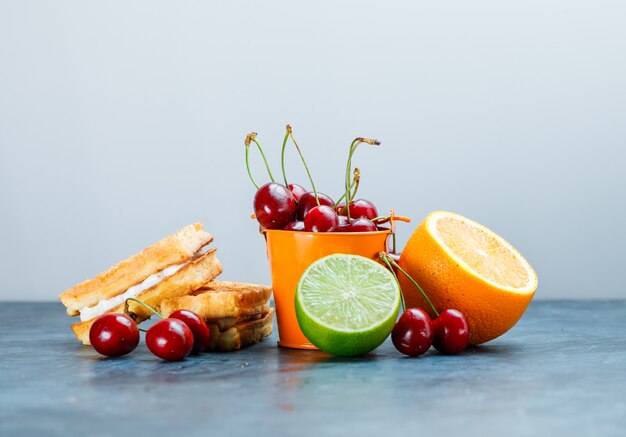 Gaufres aux cerises, orange, citron vert vue latérale sur fond bleu et blanc grungy