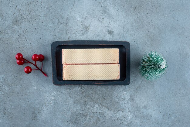 Gaufrettes dans un petit plateau à côté d'ornements de Noël sur une surface en marbre