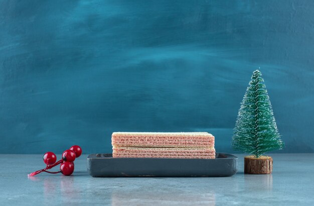 Gaufrettes fourrées à la crème de fraise dans un petit plateau à côté d'ornements de Noël sur la surface en marbre