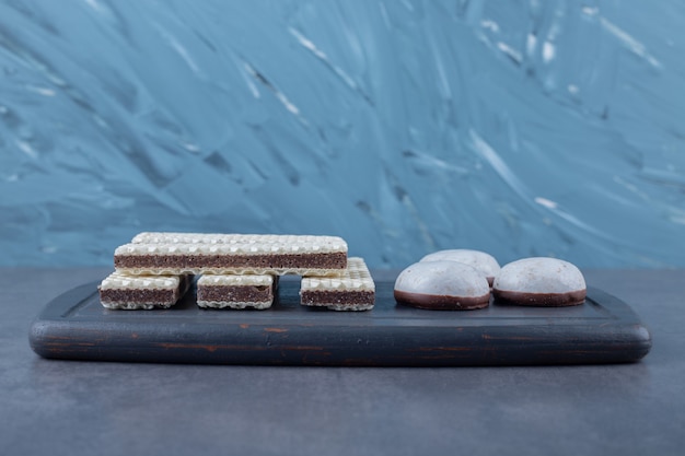 Gaufrettes et gâteaux pop sur un plateau en bois sur une table en marbre.