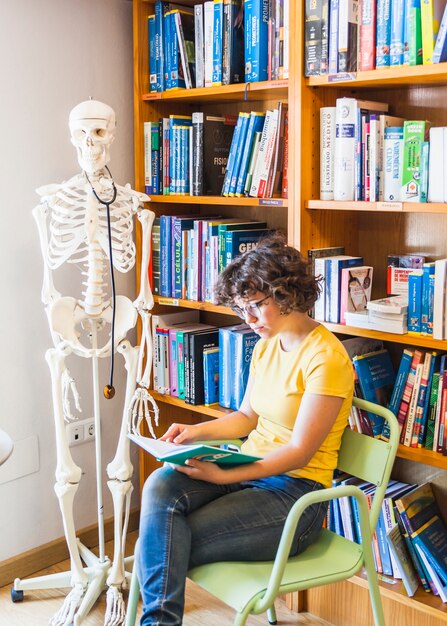 Geek femelle sur une chaise assise avec livre