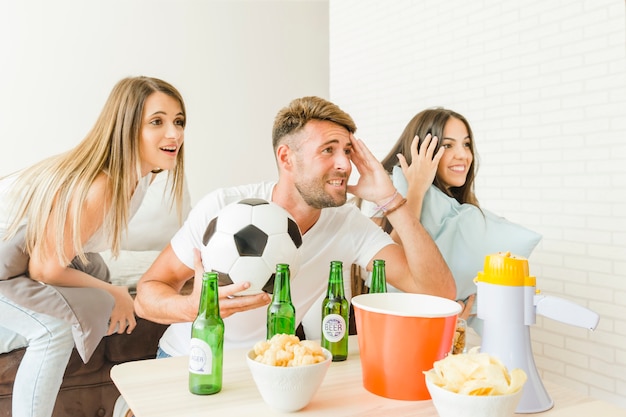 Les gens acclamant regarder match de football à la maison