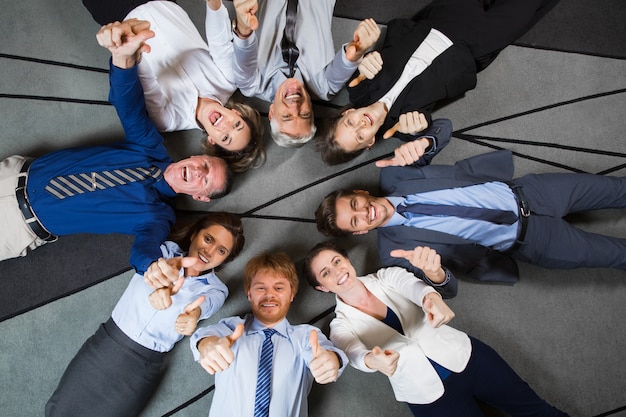 Les gens d&#39;affaires couché sur le plancher montrant thumbs up