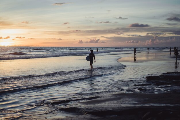 les gens au bord de l&#39;océan au coucher du soleil.