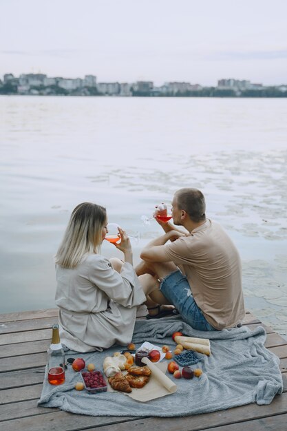 Les gens au bord de la rivière. Délicieux pique-nique d'été sain sur l'herbe. Fruits sur un blancet.