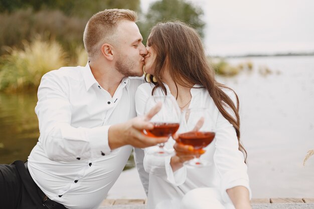 Les gens au bord de la rivière. Délicieux pique-nique d'été sain sur l'herbe. Vigne rouge.