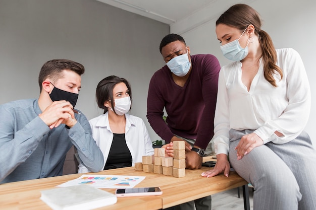Les gens au bureau pendant la pandémie ayant une réunion avec des masques médicaux sur