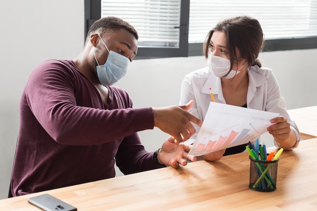 Photo gratuite les gens au travail au bureau pendant la pandémie avec des masques médicaux