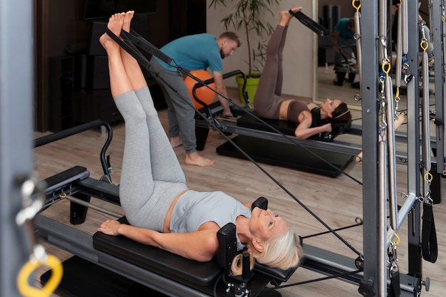 Photo gratuite les gens en classe réformateur pilates exerçant leur corps