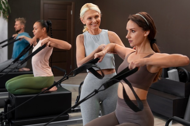 Photo gratuite les gens en classe réformateur pilates exerçant leur corps